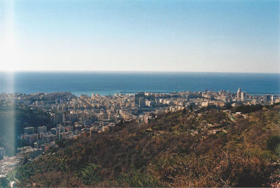 Cityscape by sea against clear sky