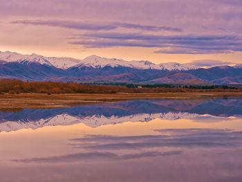 Scenic view of lake and mountains against sky during sunset