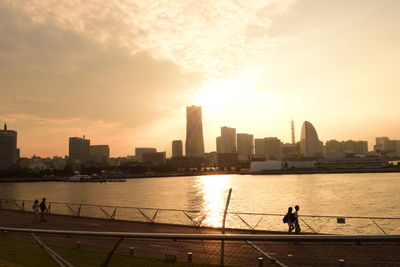 Silhouette man standing by river against sky during sunset