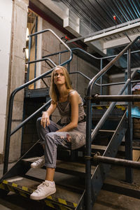 Young woman sitting on staircase in city