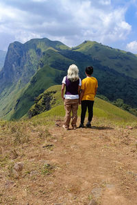 Rear view of man walking on mountain against sky