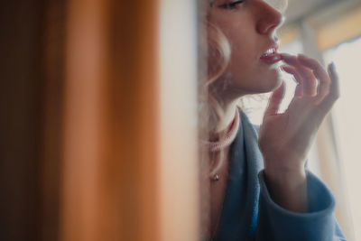 Midsection of young woman touching lips reflecting on mirror at home