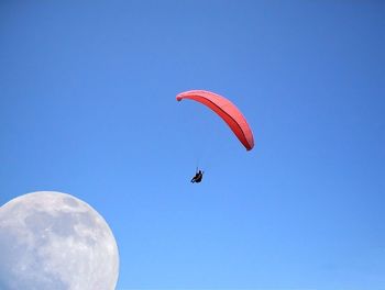 Low angle view of parachute against clear blue sky