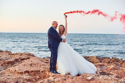 Couple kissing on beach by sea against clear sky