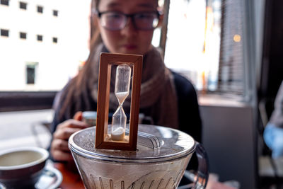 Young woman looking at hourglass on container