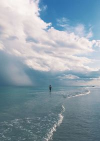 Mid distance view of person on shore at beach against sky