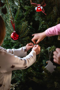 Children hands decorating christmas tree at home