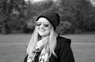 Close-up of smiling woman wearing sunglasses standing at park
