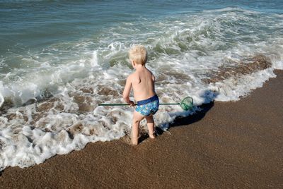 Shirtless boy fishing in sea