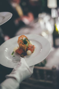 Close-up of hand holding dessert in plate at restaurant