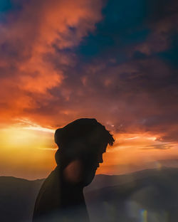 Portrait of young man standing against orange sky