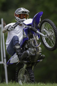 Forward quarter view of young man riding a wheelie on an off-road motorcycle