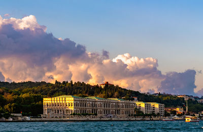 Sea by buildings in city against sky