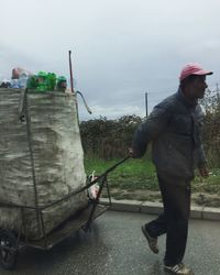 Man working with arms outstretched against sky