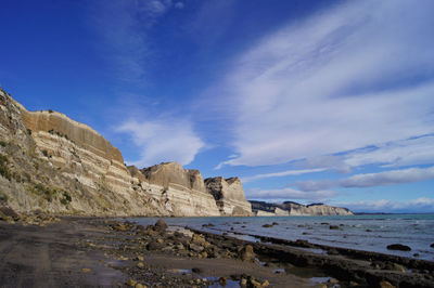 Idyllic shot of cliff by sea against sky