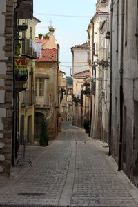 Alley amidst buildings against clear sky