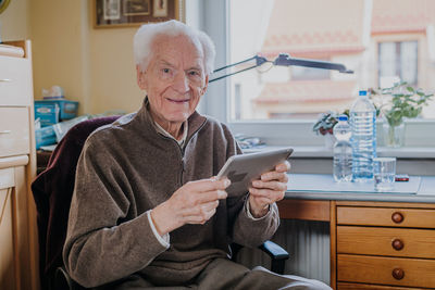 Portrait of smiling senior man using digital tablet at home