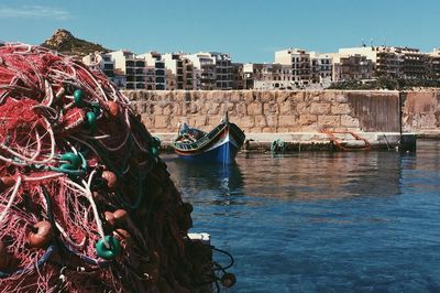 Fishing boats moored at harbor against sky