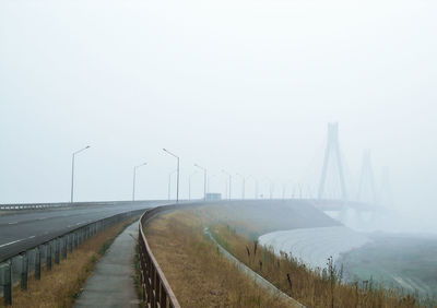 Road to the bridge covered in strong fog at the daylight