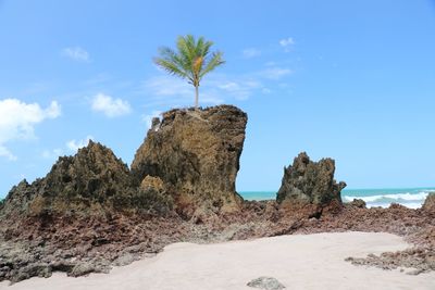 Rock formations on beach against sky