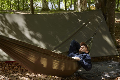 Man sleeping on hammock in forest