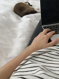 Midsection of woman using laptop on bed