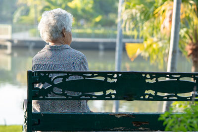Rear view of woman sitting on railing