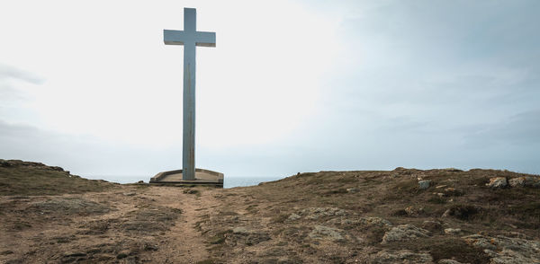 Low angle view of cross on mountain against sky