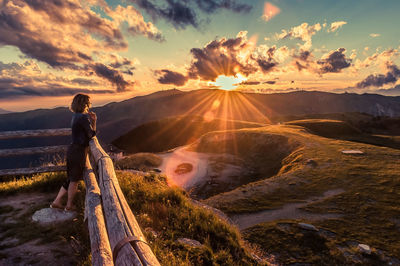 Man standing on mountain against sky during sunset