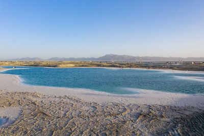 Scenic view of beach against clear blue sky
