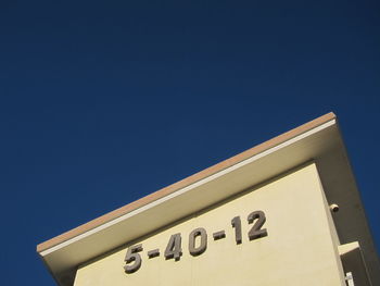 Low angle view of sign against clear blue sky