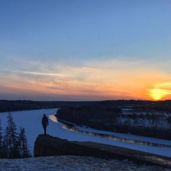 Silhouette woman standing by sea against sky during sunset
