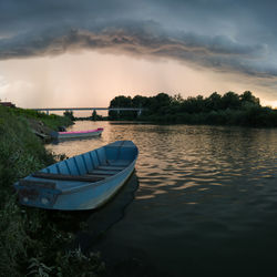 Boat moored in lake against sky during sunset