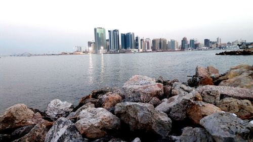 Sea by cityscape against sky