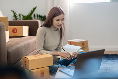 Young woman using laptop while sitting on sofa at home