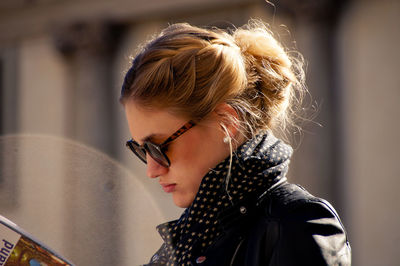 Side view of young woman reading book on sunny day