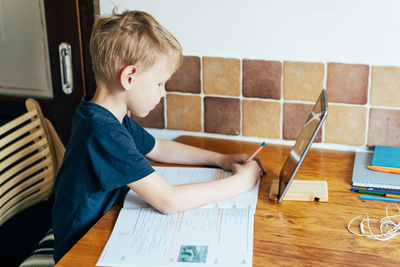 Side view of boy sitting on table