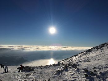 People on snowcapped mountain against sky