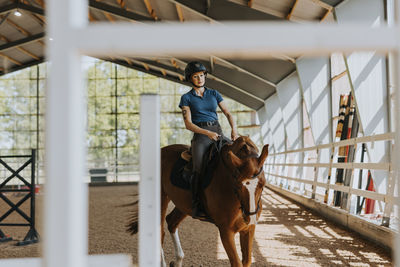 View of female horse rider using indoor riding paddock