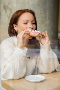 Young woman eating food while sitting on table