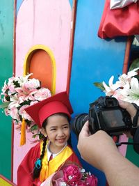 Cropped parent photographing cute girl in graduation gown