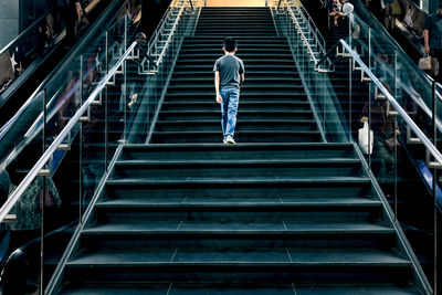 Rear view of man walking on staircase