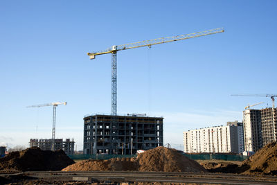 Crane at construction site against sky in city