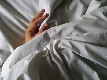 High angle view of hand on bed