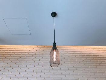 Low angle view of light bulb hanging on wall