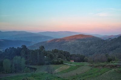 Scenic view of field and mountains against sky during sunset