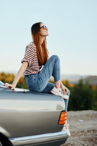 Young woman sitting on car