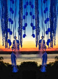 Multi colored decoration hanging against blue sky at sunset