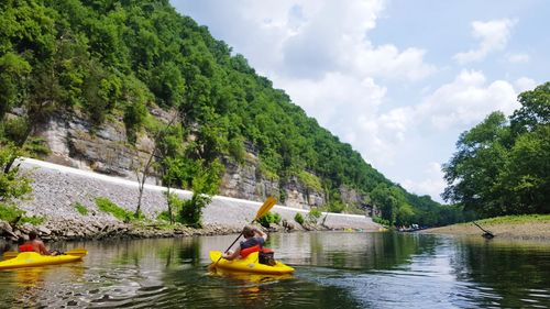 People boating on river against sky