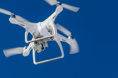 Low angle view of drone flying against clear blue sky